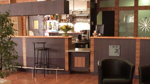 Una zona de bar con taburetes, una cafetera y un jarrón decorativo con flores.