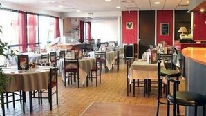 Un restaurante con varias mesas y sillas, piso de baldosas y paredes rojas.