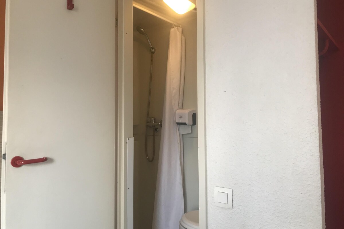 A bathroom with a shower, toilet, and a hand dryer.