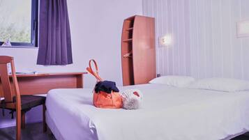 A hotel room with a bed, a desk, and a chair.
