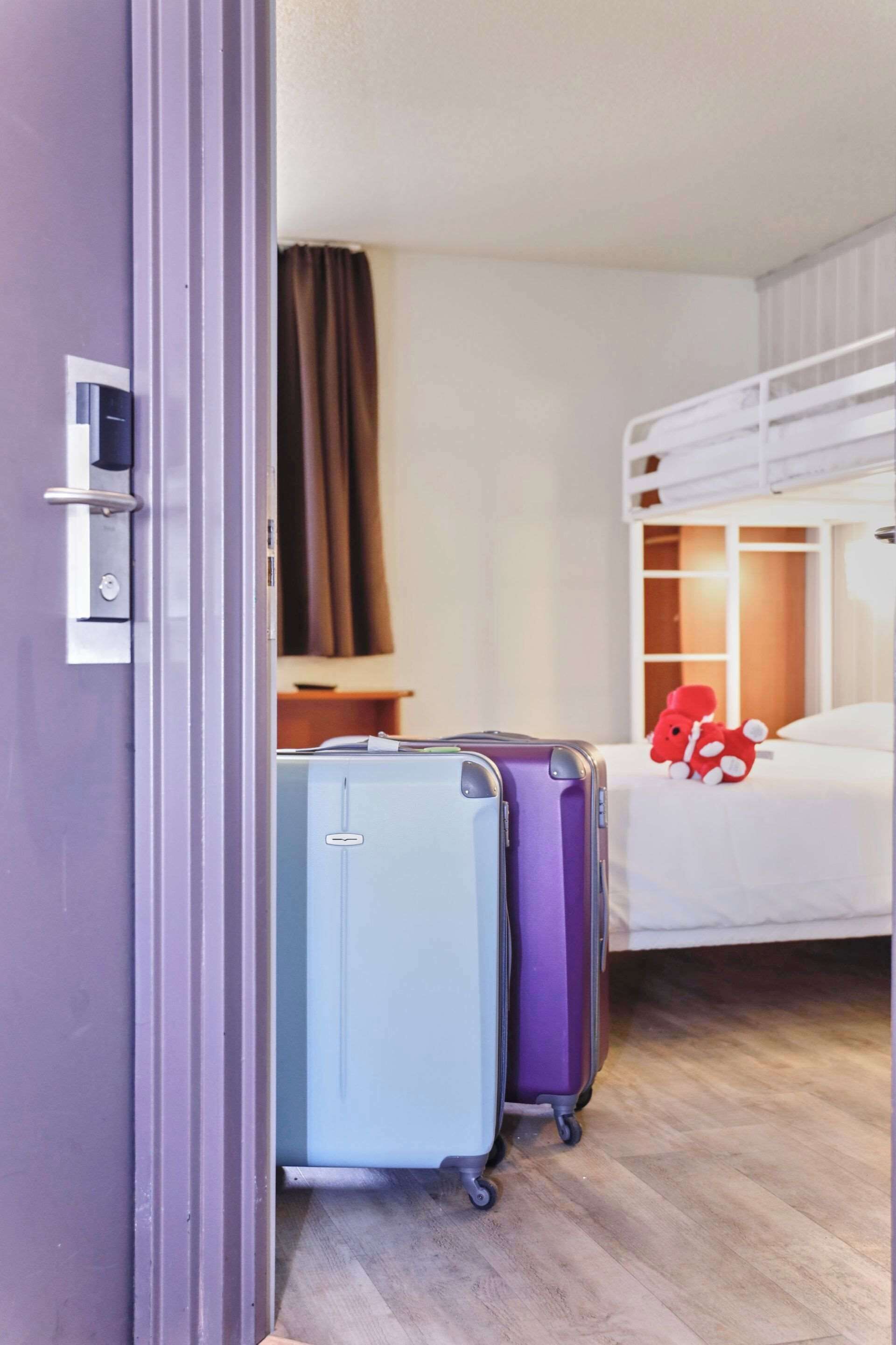 Habitació d'hotel amb una llitera, un escriptori i dues maletes.