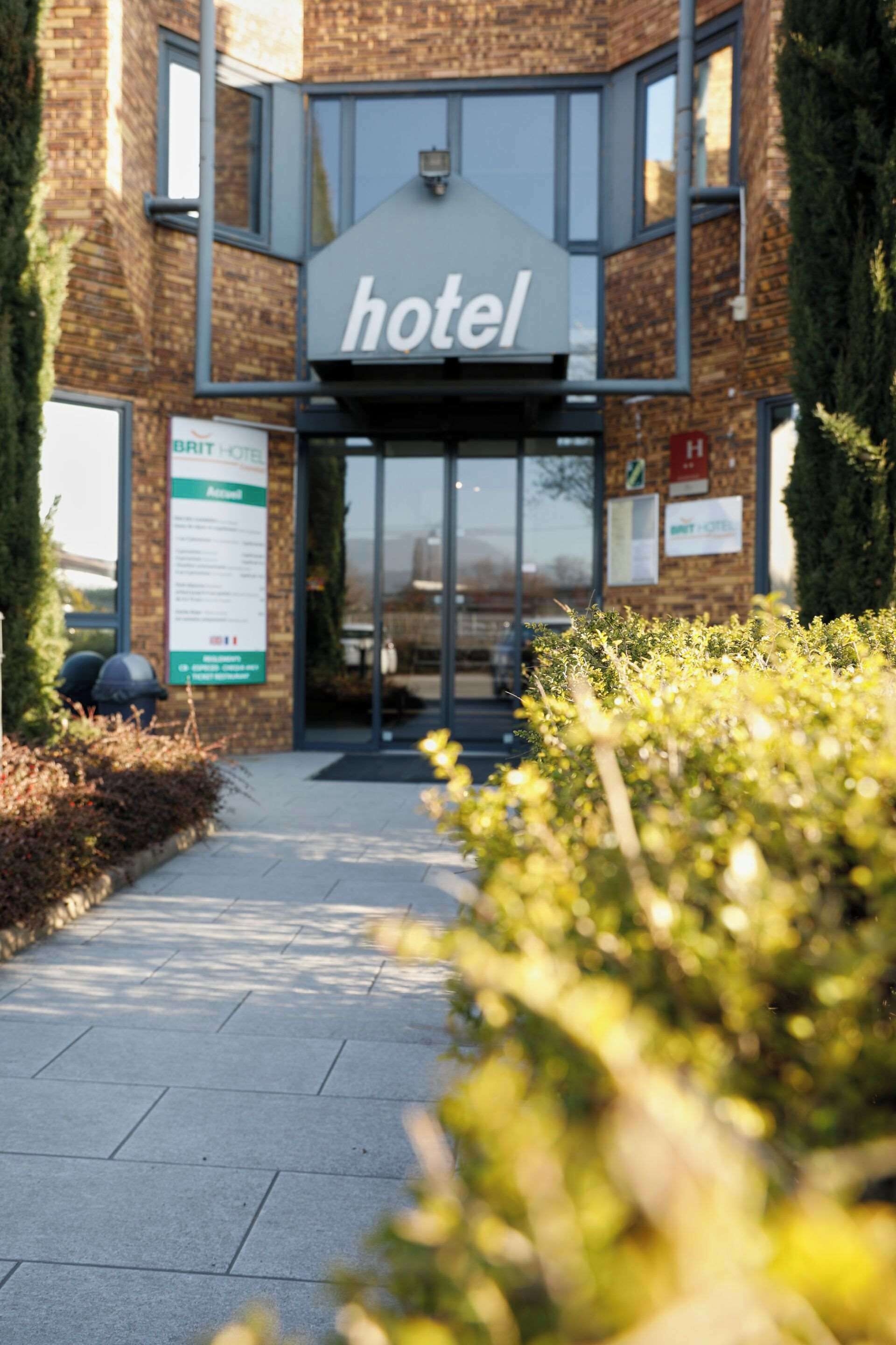 Een hotelentree met een bord met daarop de tekst ‘hotel’ boven de deur, een gevel van baksteen en een pad dat naar de entree leidt.