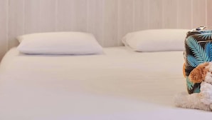 A hotel room with a wooden wall, two bedside lamps, a bed with white bedding, and a small decorative item on the bed. - Brit Hotel Chambery (Chambery)