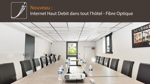 A conference room with a long table, chairs, a projector, and water bottles. - Brit Hotel Chambery (Chambery)
