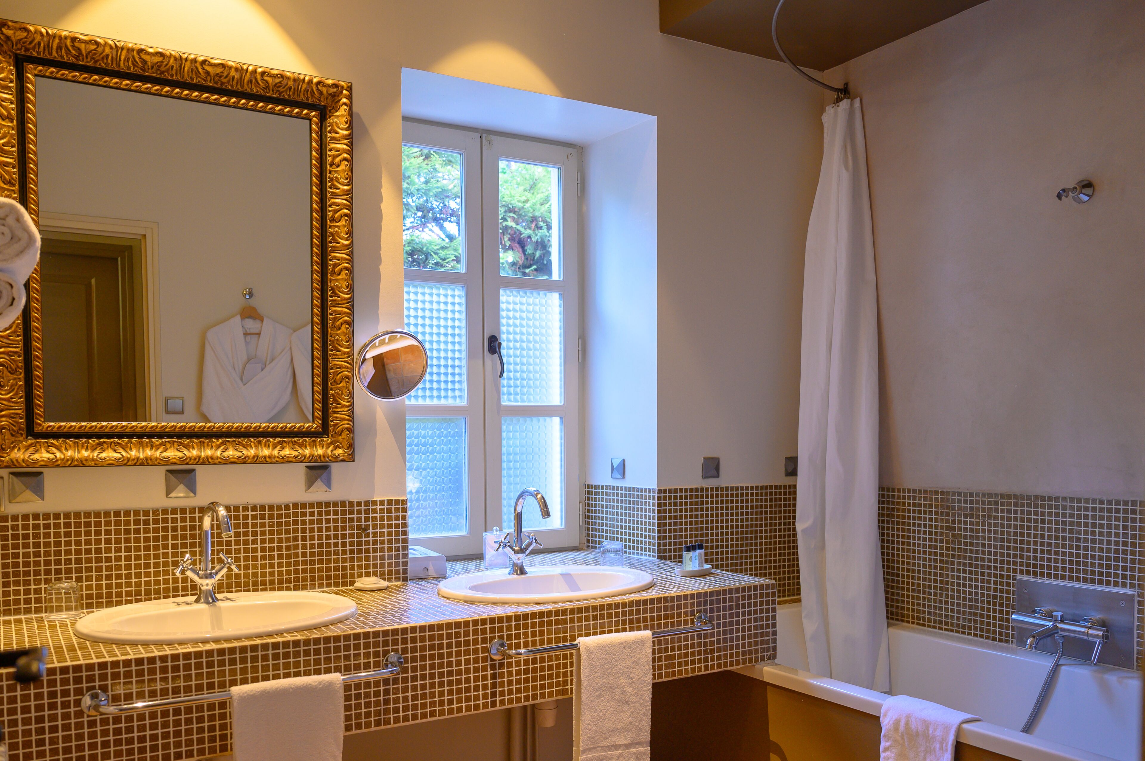 A bathroom with two sinks, a large mirror, and a shower.