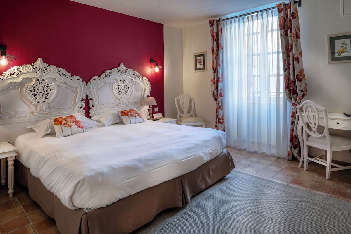A hotel room with a large bed, a desk, and a chair.