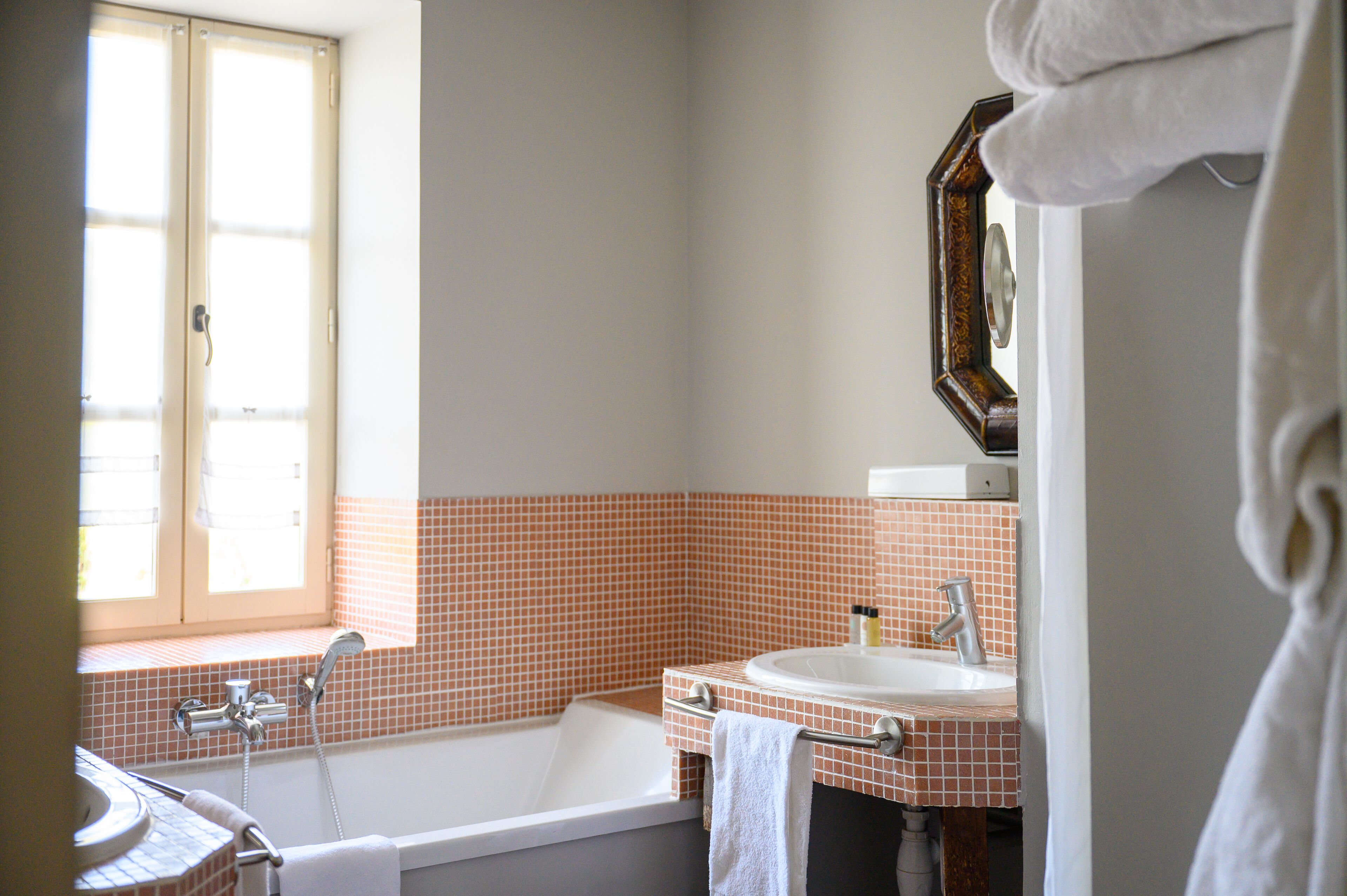 A bathroom with a bathtub, a sink, and a window.