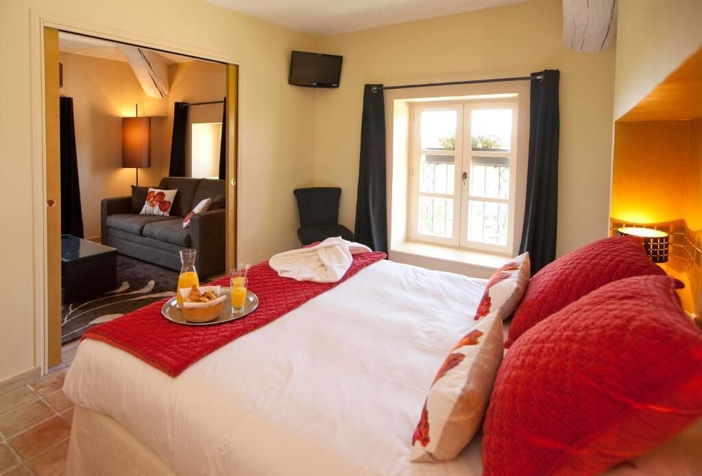 Une chambre d’hôtel avec un lit, une télévision, une fenêtre avec des rideaux et un balcon.