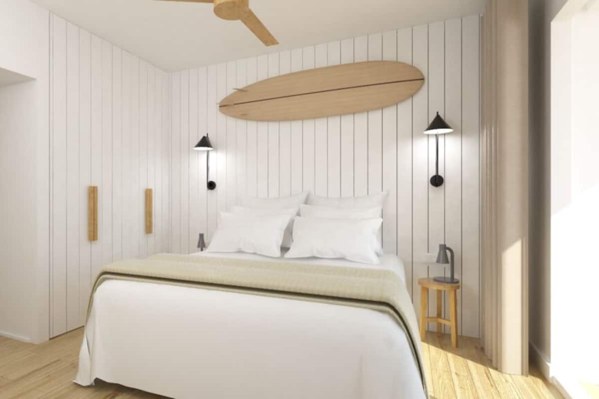 Ein Schlafzimmer mit einem Bett, zwei Wandleuchten, einem Deckenventilator und Holzboden.