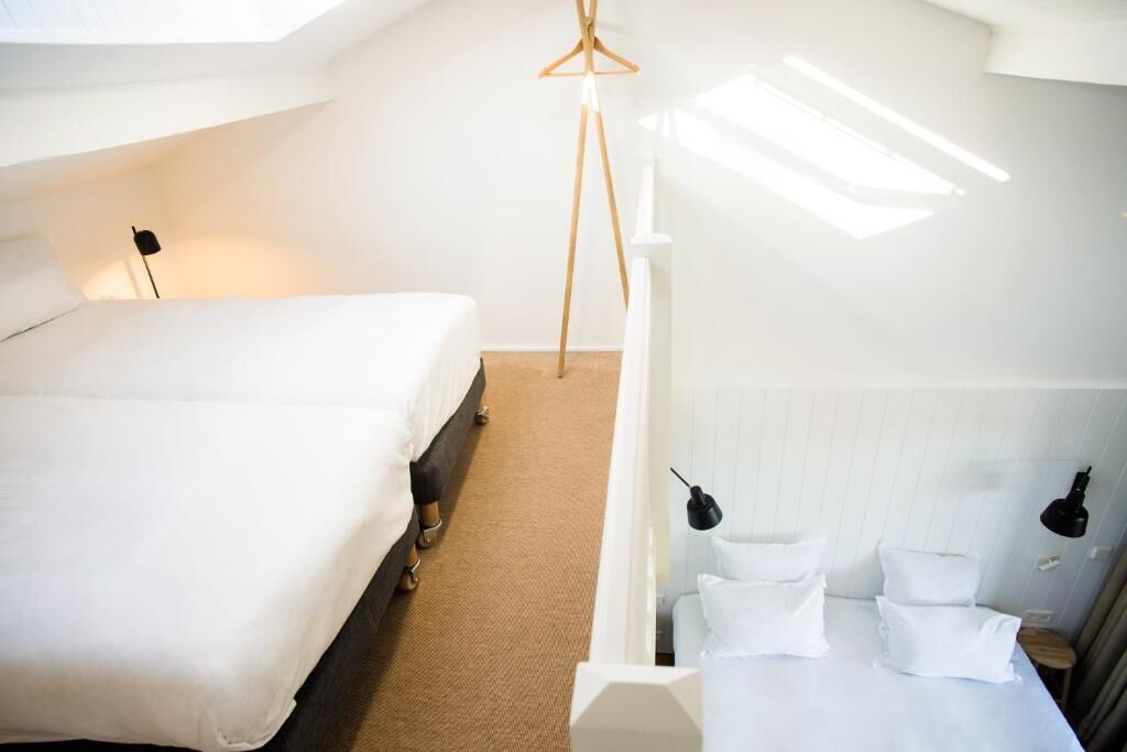 A bedroom with a bed, a hanging light, and a small table with pillows.