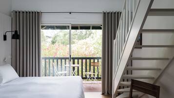 Une chambre avec un lit, un balcon avec une table et des chaises, et un escalier.