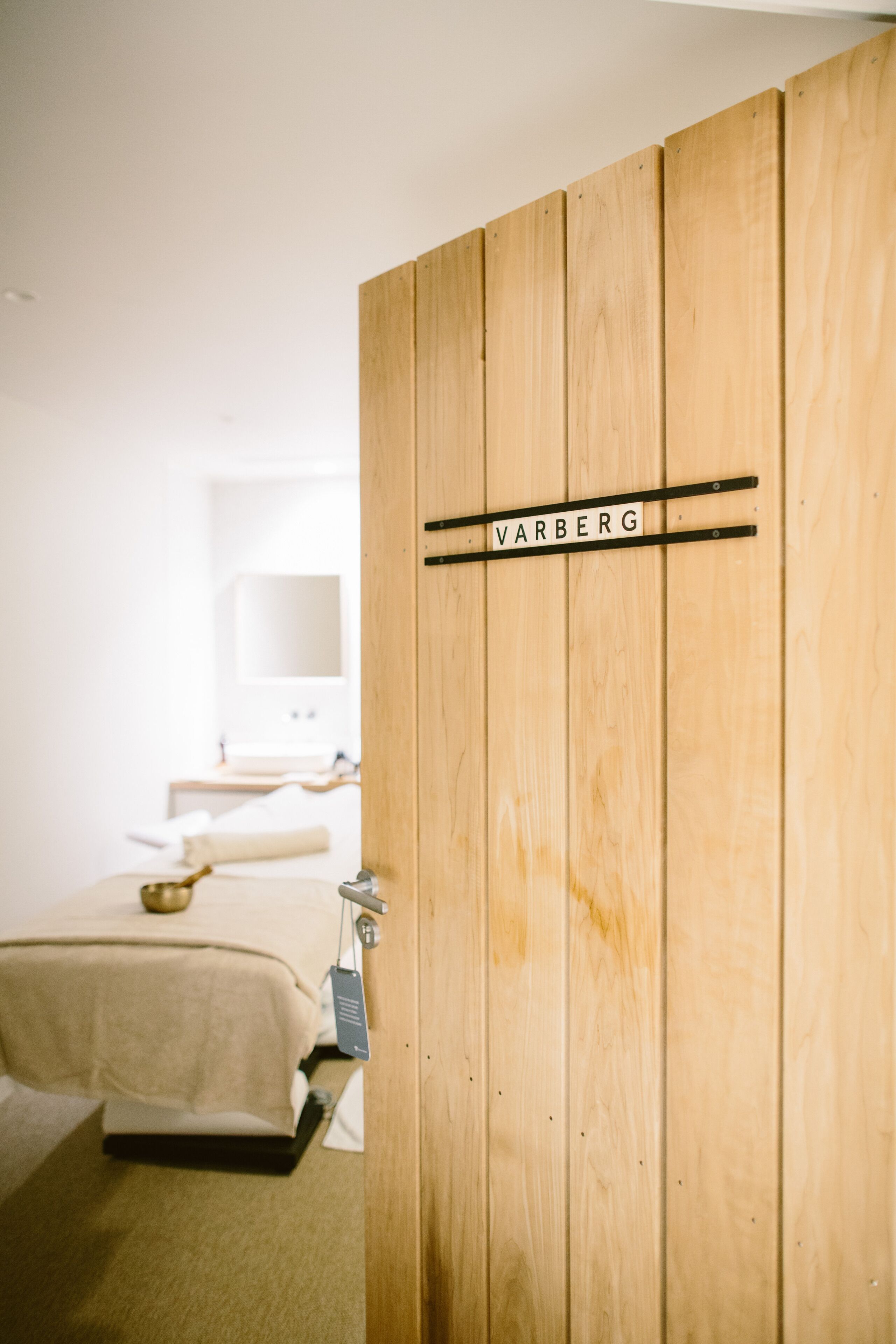 A wooden wardrobe with a name tag reading "VARBERG" in a hotel room.