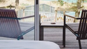 Une terrasse avec deux chaises et une table, donnant sur une piscine et des arbres.