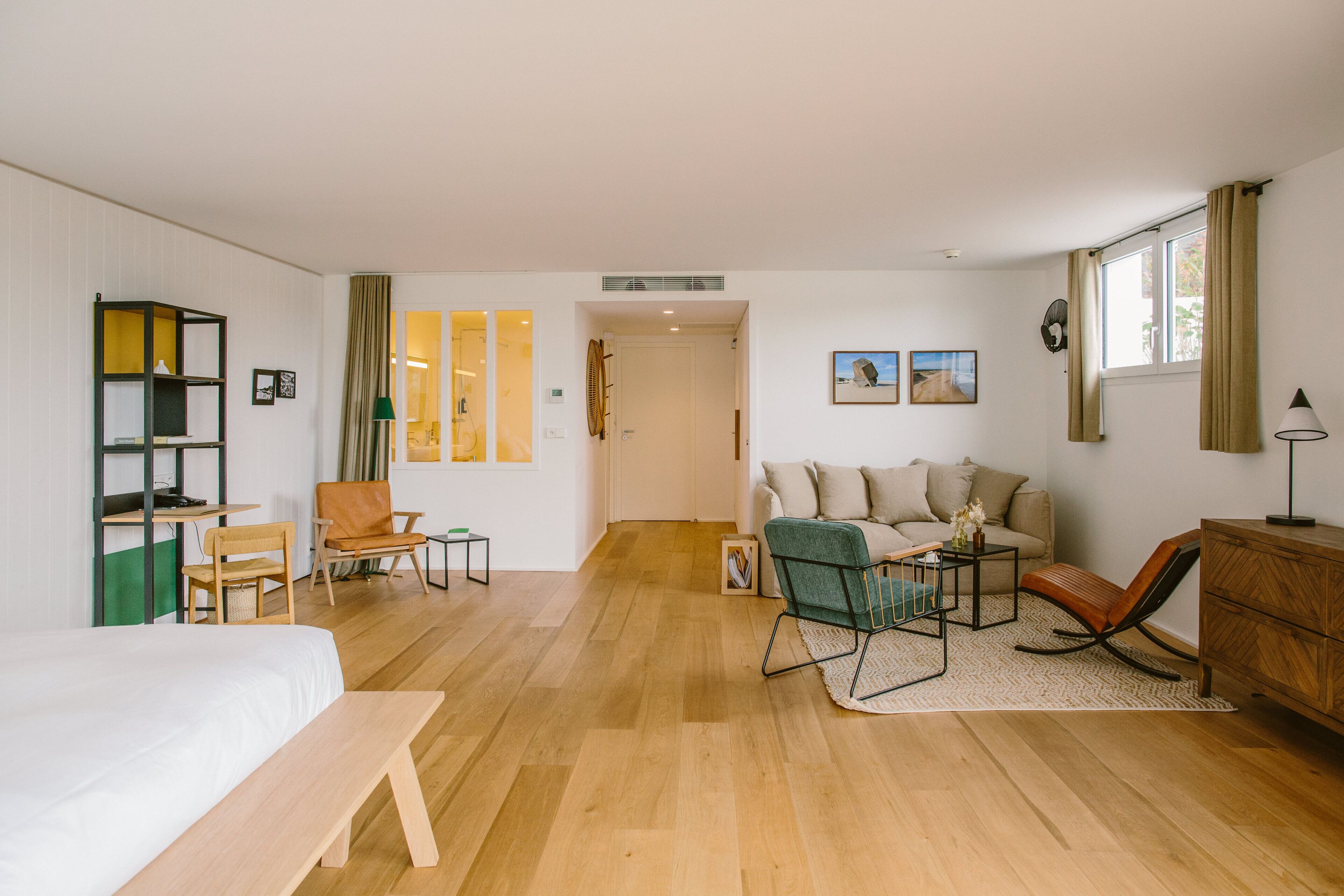 Een ruime kamer met een bed, een bureau, een stoel, een bank en een dressoir.