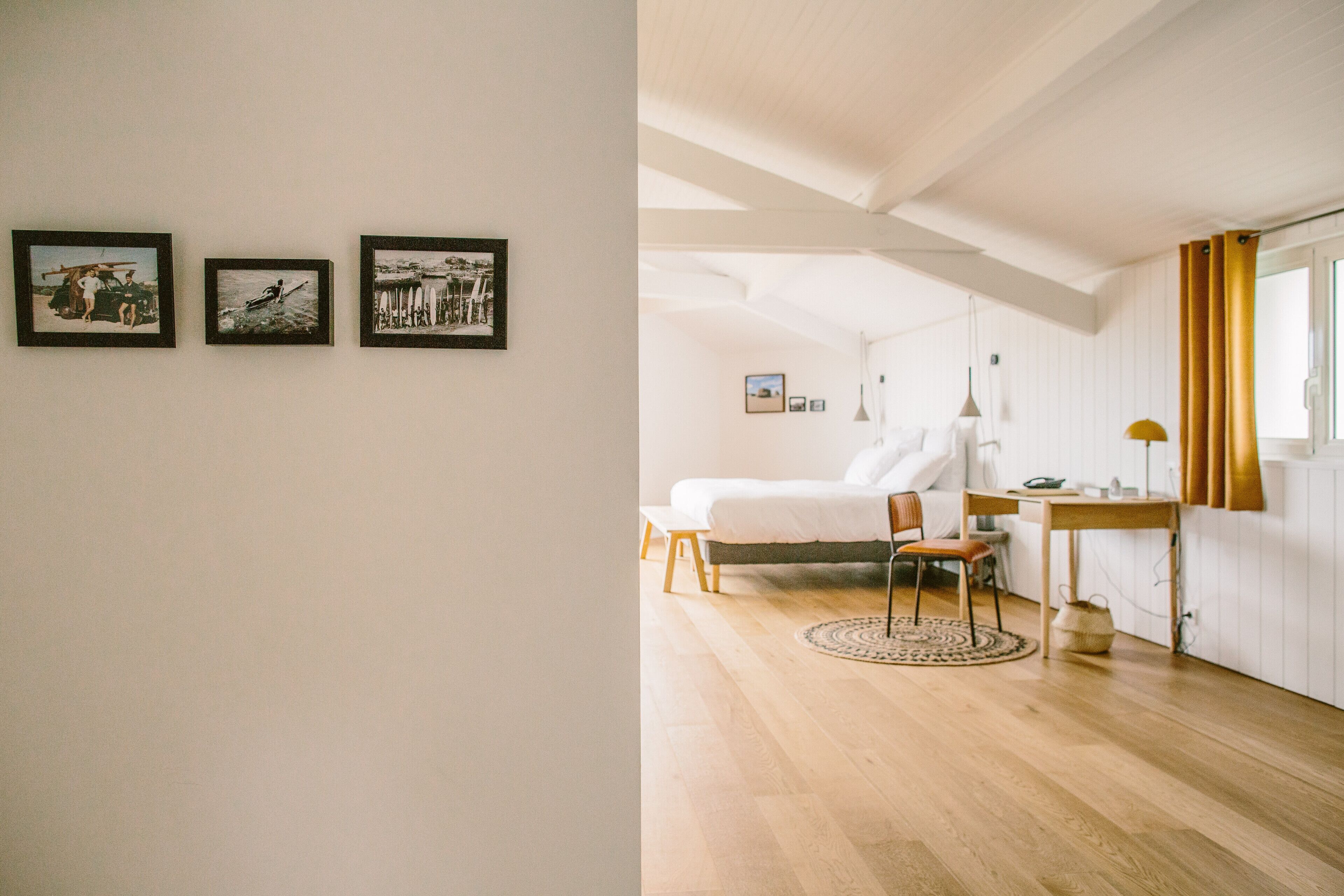 A bedroom with a bed, a chair, a table, and a window with curtains.