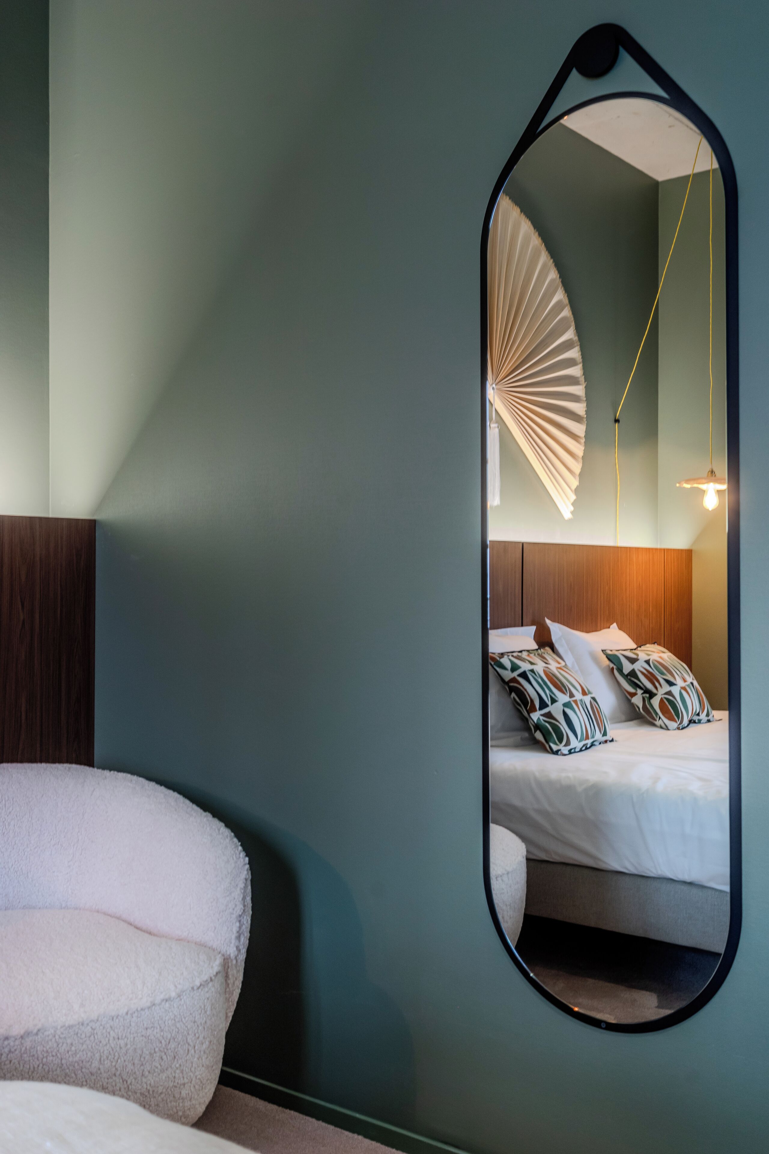 Un dormitorio con cama, un espejo grande y un ventilador de techo.