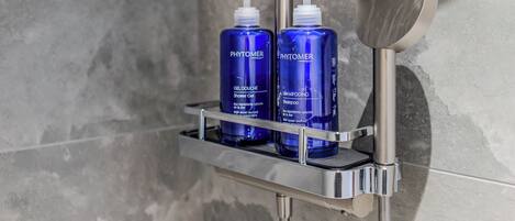 Two blue PHYTOMER bottles on a chrome shelf in a shower area.