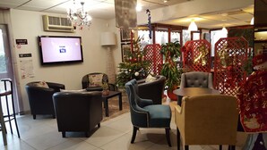 Un área de descanso moderna con asientos cómodos, un televisor de pantalla plana y un árbol de Navidad decorado.