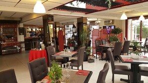 A restaurant interior with tables, chairs, and a bar area. - Hôtel Eclipse (Magnanville)