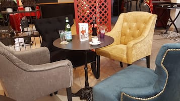 Un espace salon avec une table ronde, des chaises et un paravent décoratif en treillis rouge.