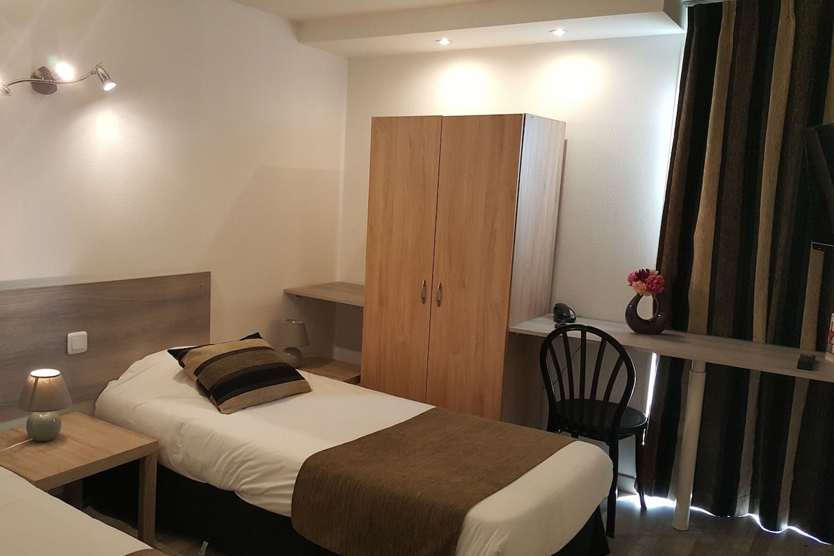 Un dormitorio ordenado con cama, mesita de noche, lámpara y un armario de madera.