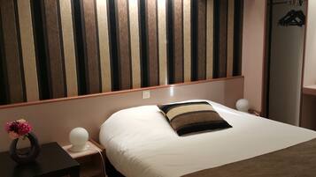A hotel room with a bed, bedside tables, a nightstand, a lamp, a dresser, and a mirror.