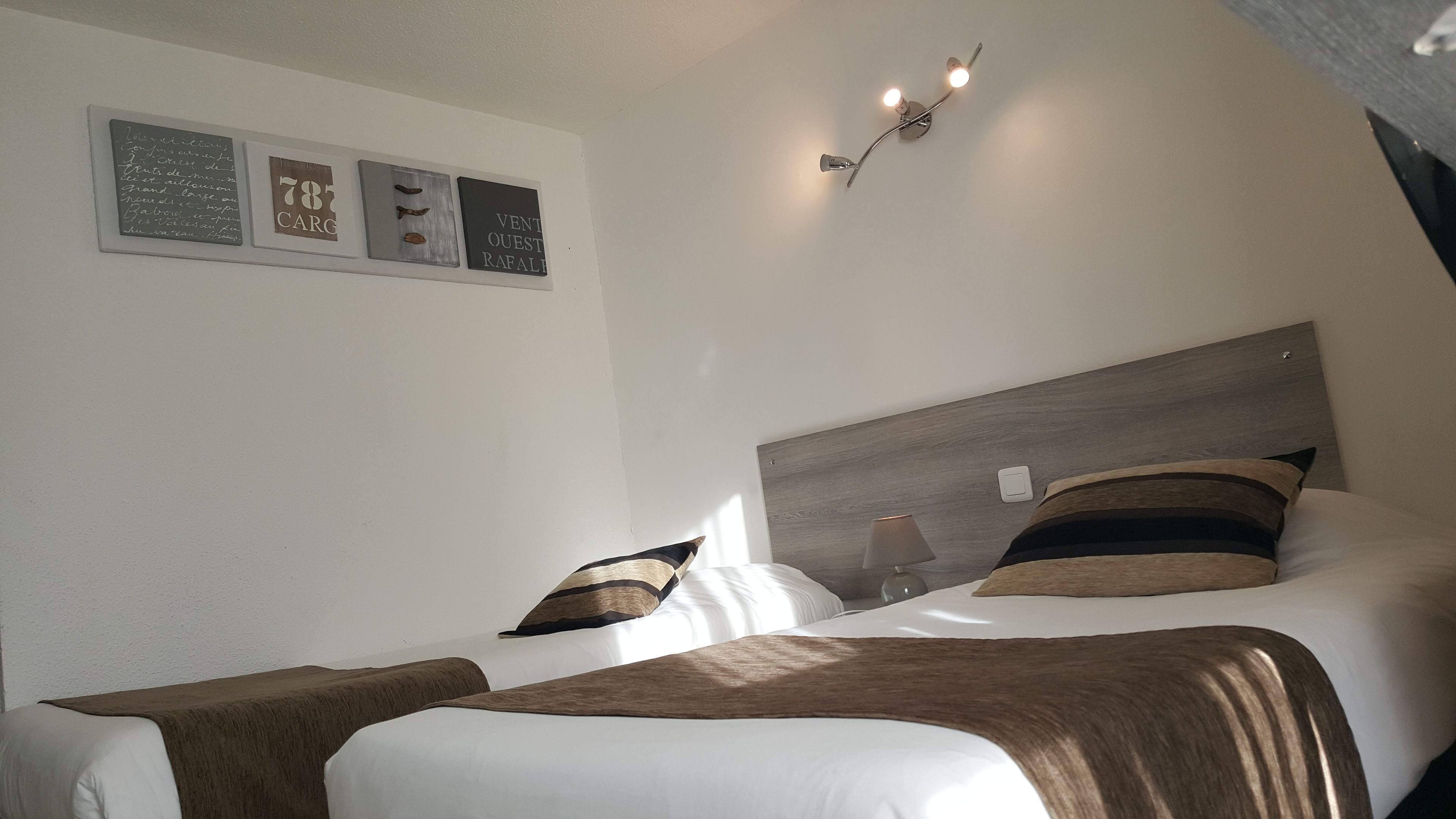 A hotel room with a bed, two bedside tables, a lamp, and wall art.
