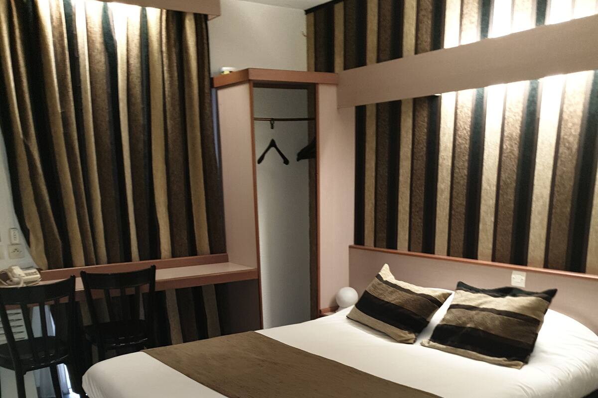 Un dormitorio ordenado con cama, escritorio y armario.