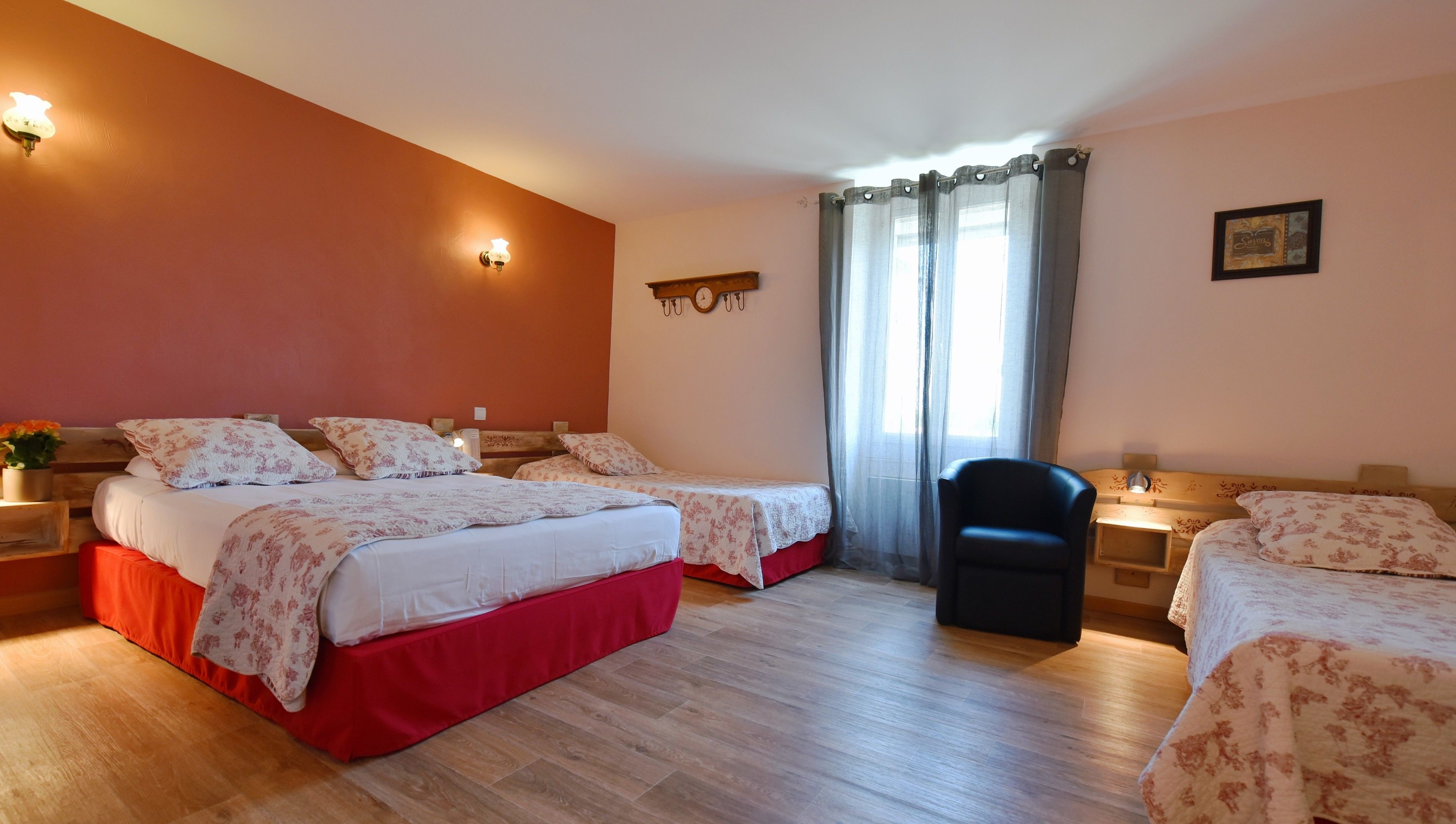 Une chambre d’hôtel avec deux lits, une chaise, une horloge et une fenêtre avec des rideaux.