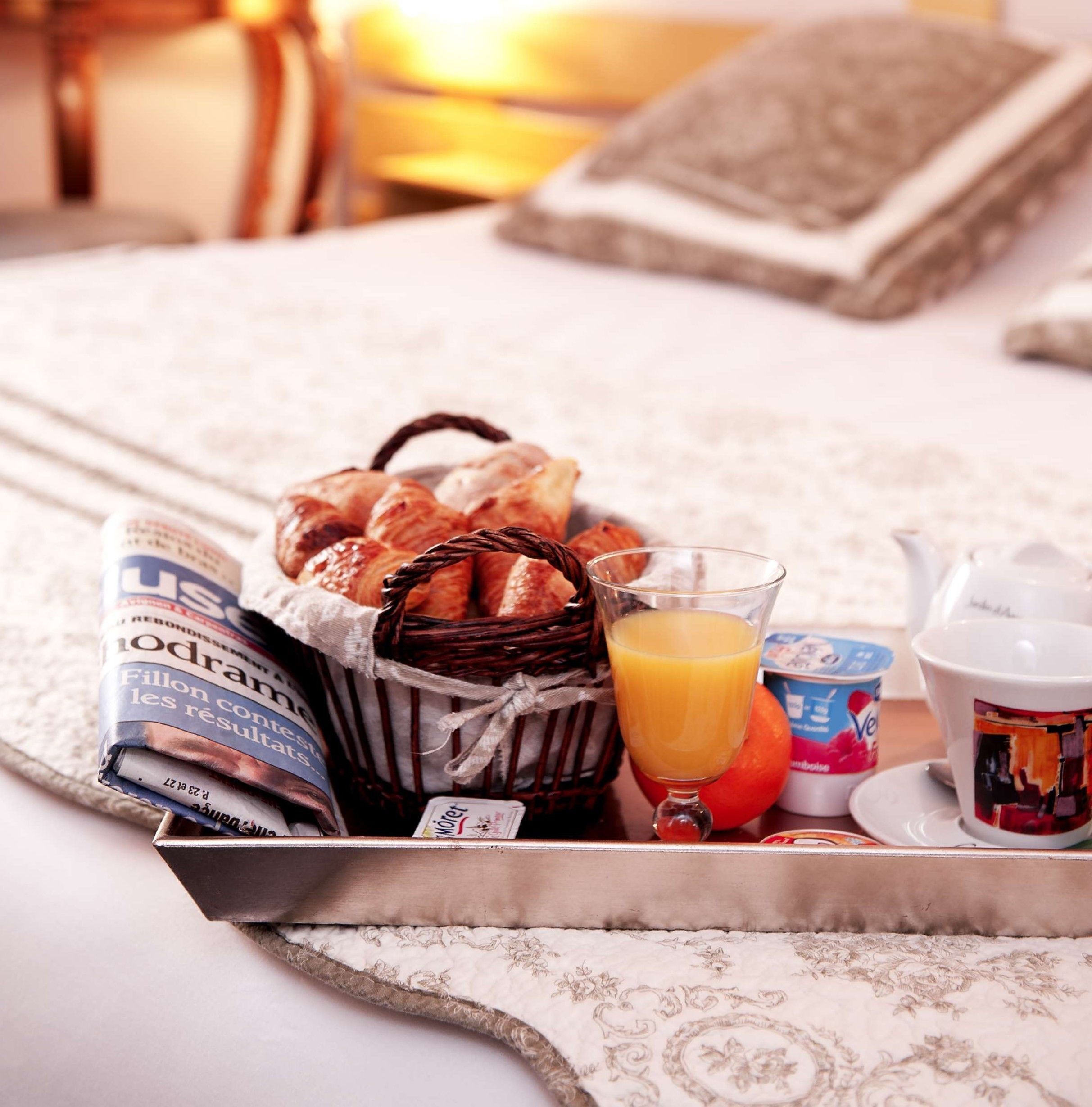 A breakfast tray with croissants, orange juice, and a newspaper.