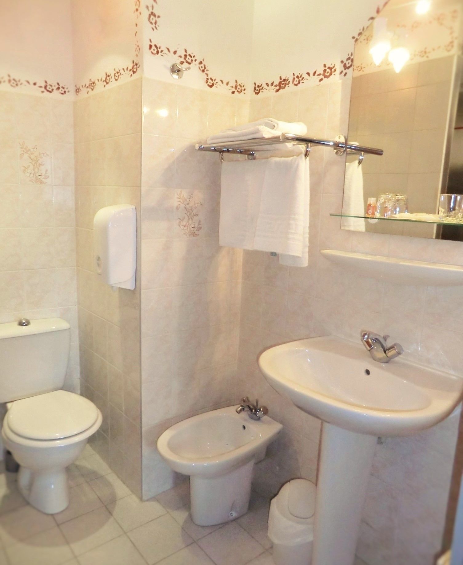 A bathroom with a toilet, bidet, and sink, all in white.