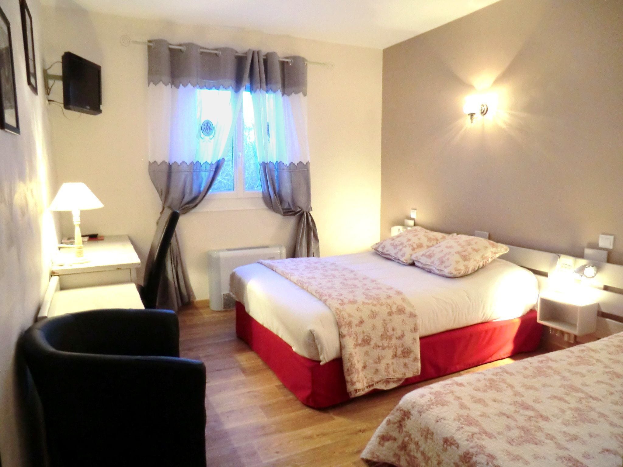 Une chambre à coucher avec un lit, des tables de chevet, une lampe, une chaise et une fenêtre avec des rideaux.
