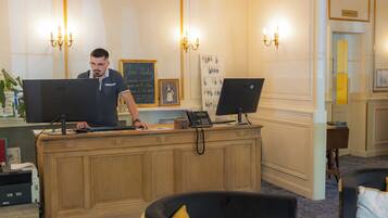 Un comptoir d’accueil équipé de deux ordinateurs, d’un tableau encadré et d’un présentoir à clés fixé au mur.