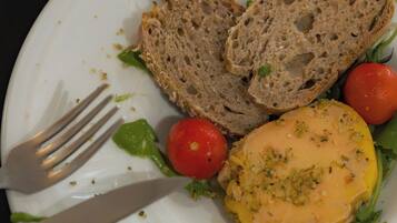 A plate with slices of bread, a tomato, and a yellow spread, possibly a type of cheese or dip.