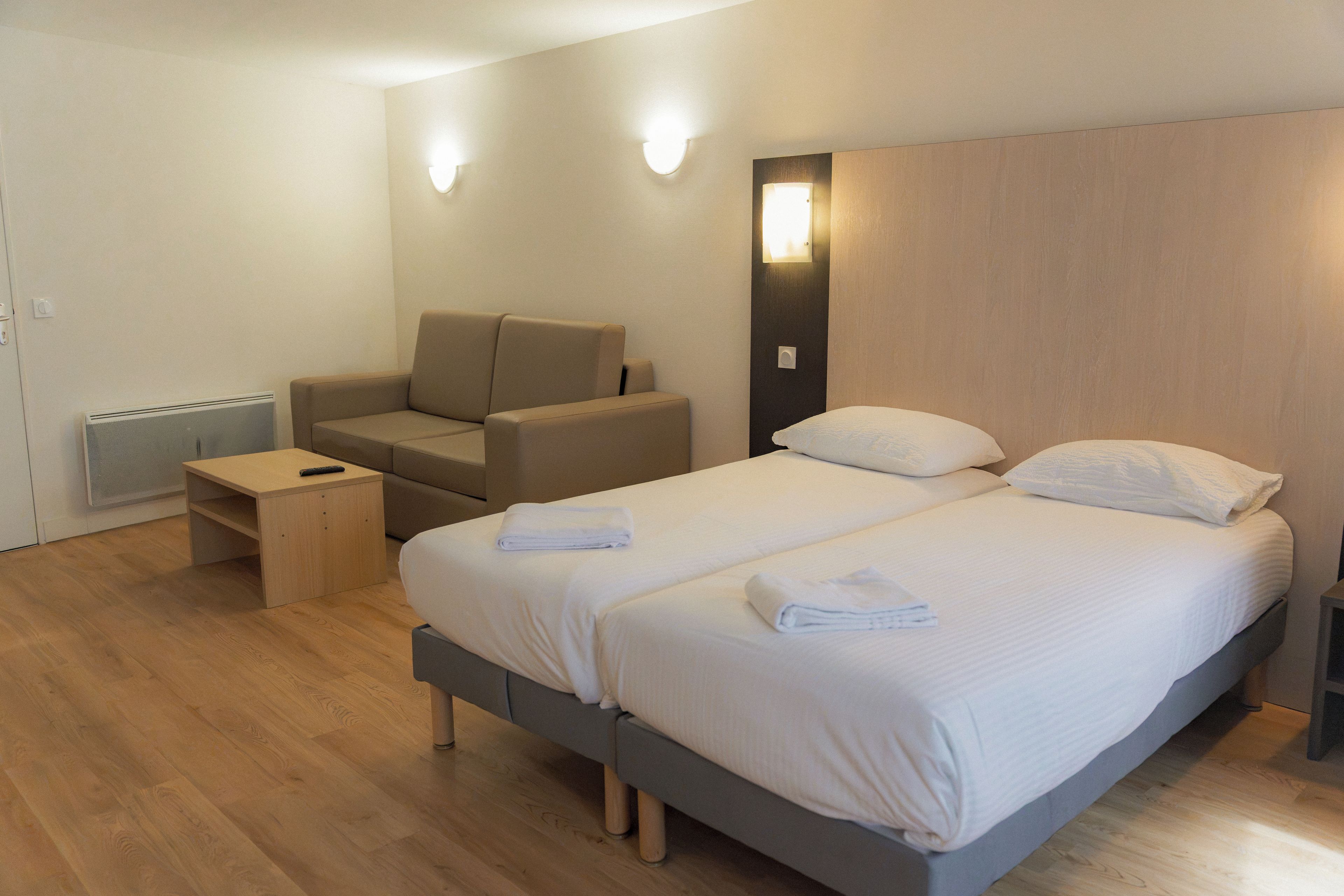 Una habitación de hotel moderna con cama, sofá, una mesita y un calentador instalado en la pared.