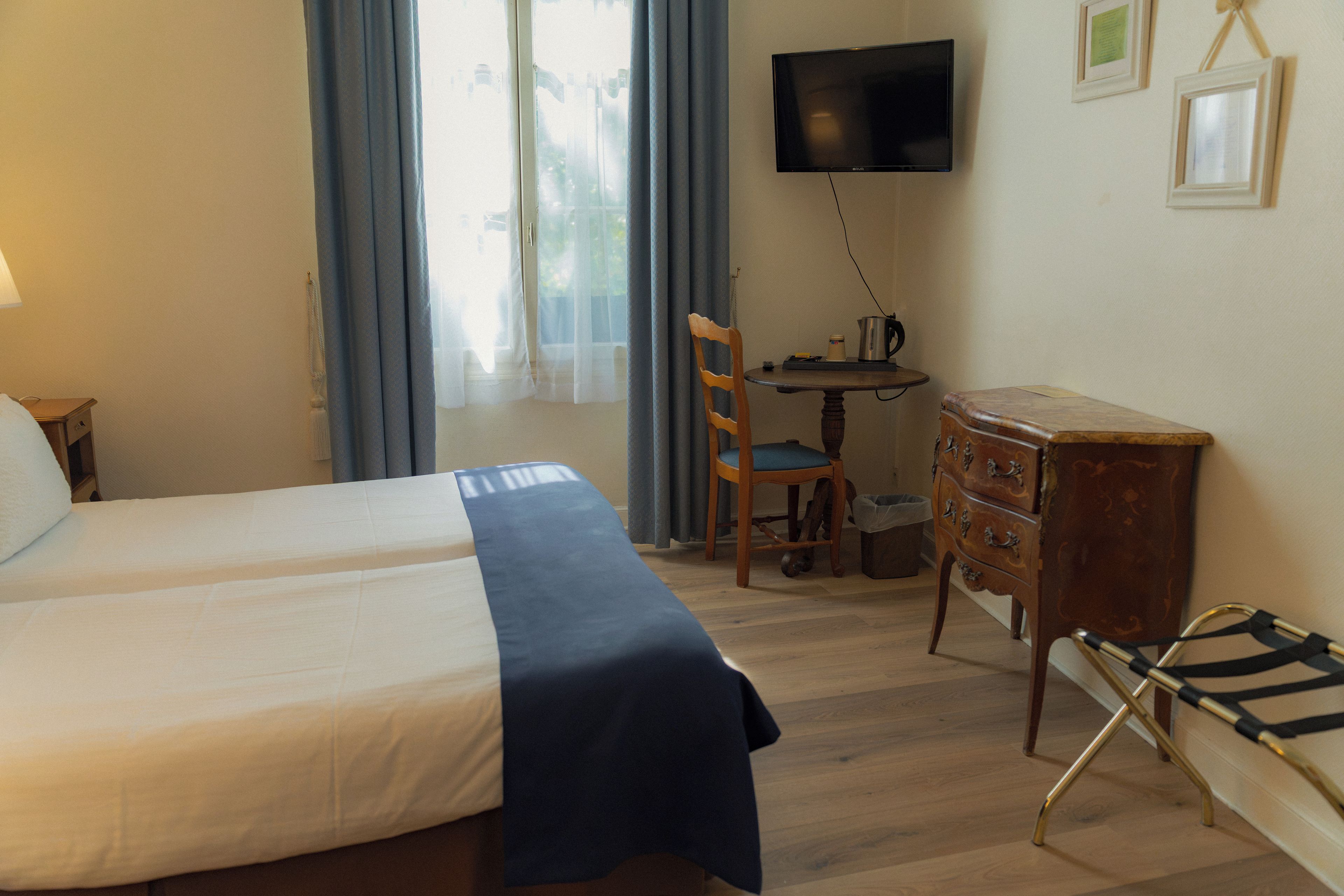 Una habitación de hotel con cama, escritorio con silla, televisor y cómoda.