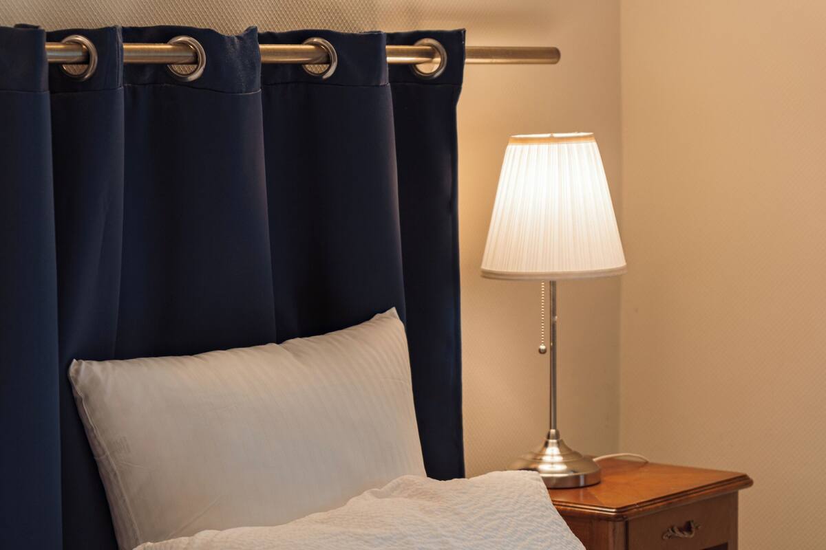 Une chambre d’hôtel avec un lit, une lampe de chevet et une table de chevet.