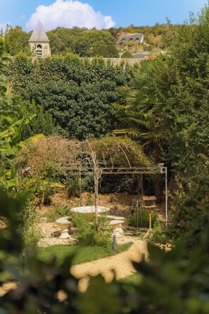 A garden with a stone structure, a pathway, and a distant building.