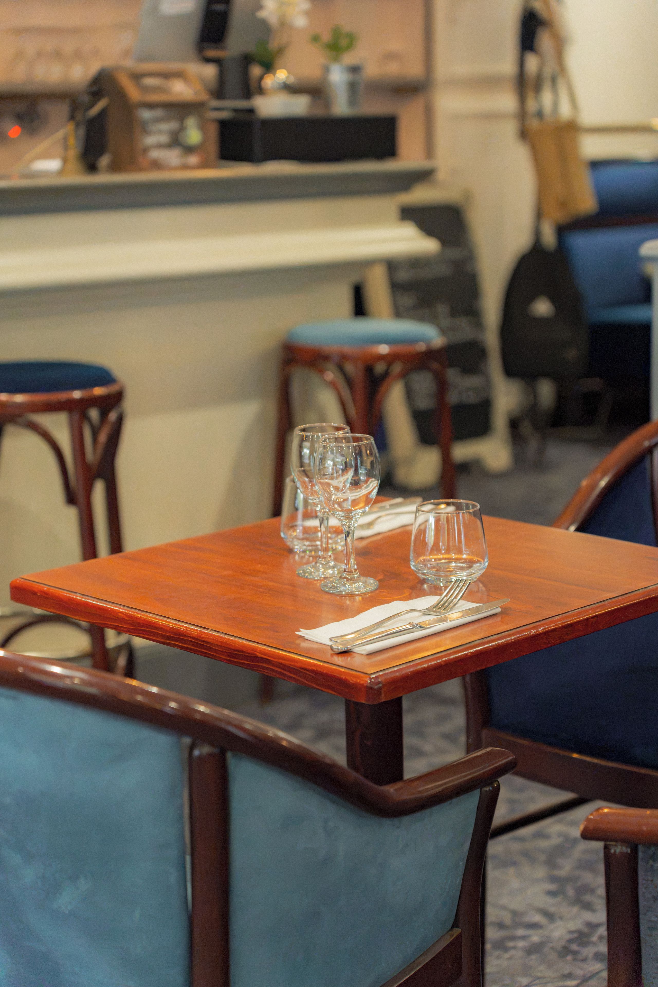 Een eetgedeelte met een tafel voor twee personen, twee stoelen en een barretje op de achtergrond.