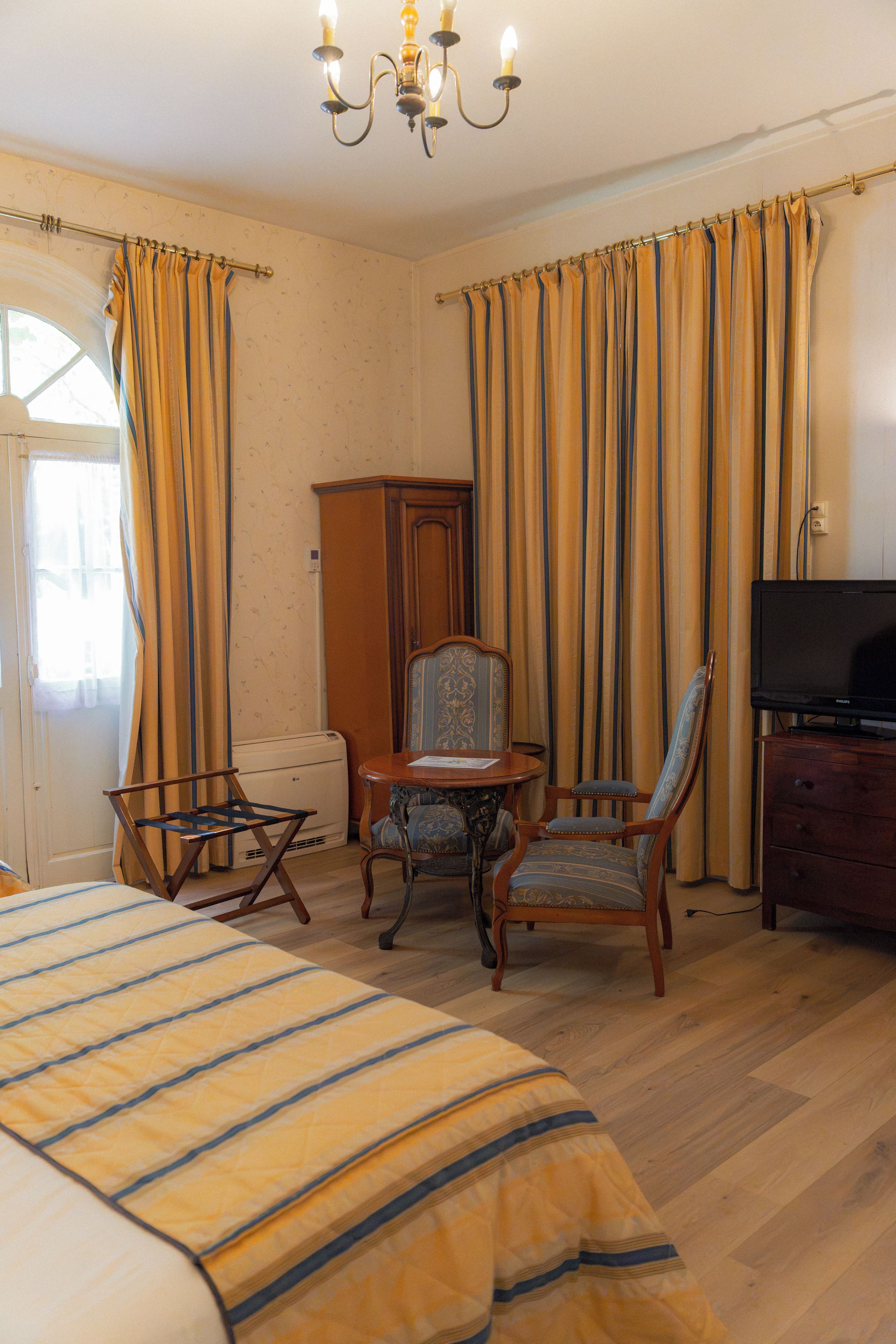Een hotelkamer met een bed, een bureau, een stoel, een televisietoestel en gordijnen.