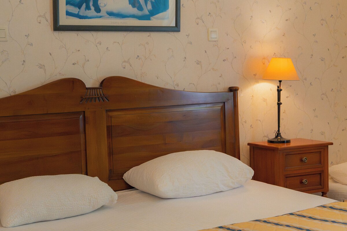 Un lit bien fait, avec une couvre-lit à rayures, une tête de lit en bois et un tableau encadré accroché au mur.