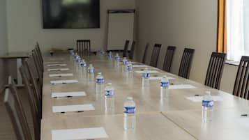 A conference room with a long table, chairs, water bottles, and papers.