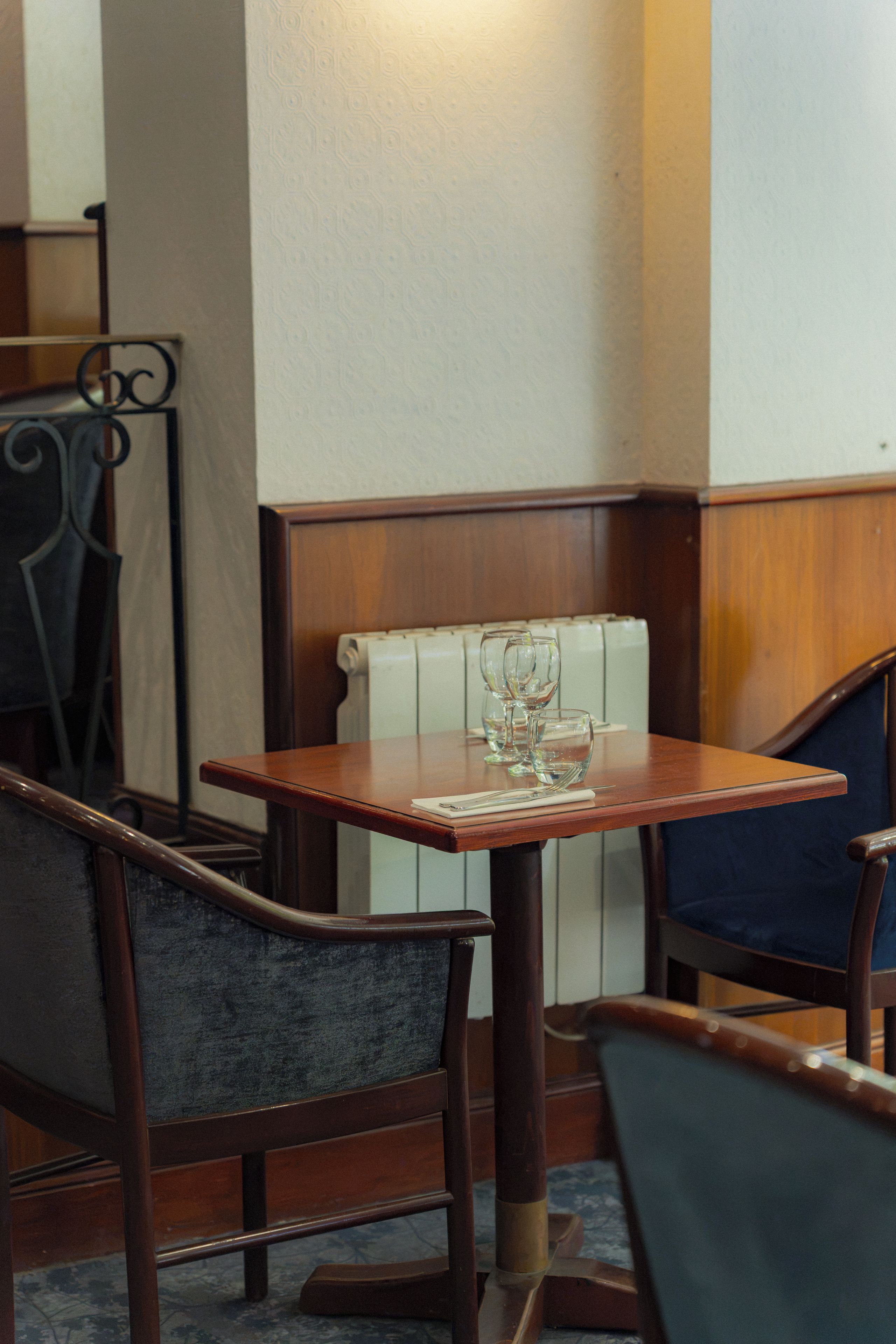 A corner of a room with a wooden table, two upholstered chairs, and a white radiator.