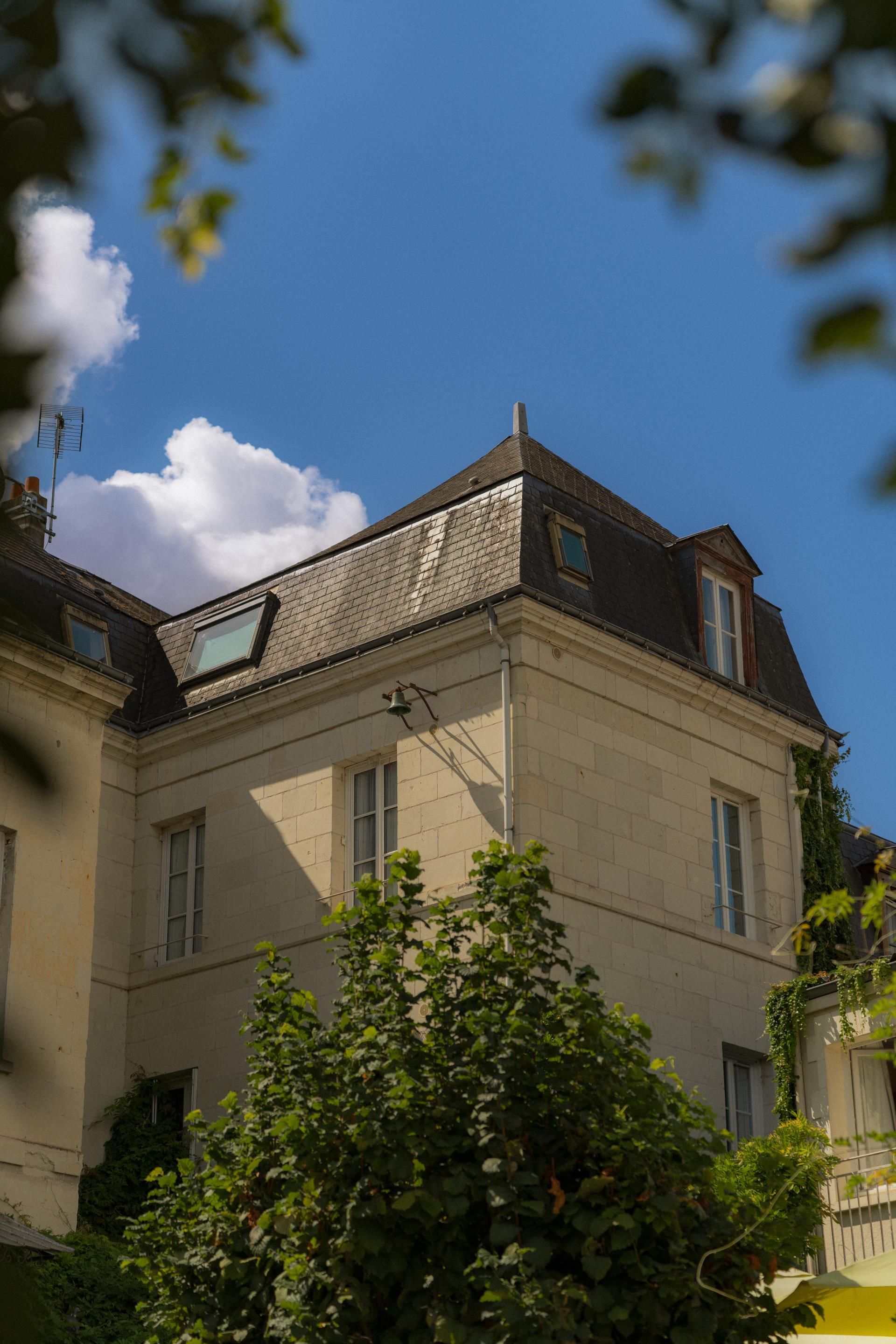 A building with a sloped roof, multiple windows, and a bell on the roof.