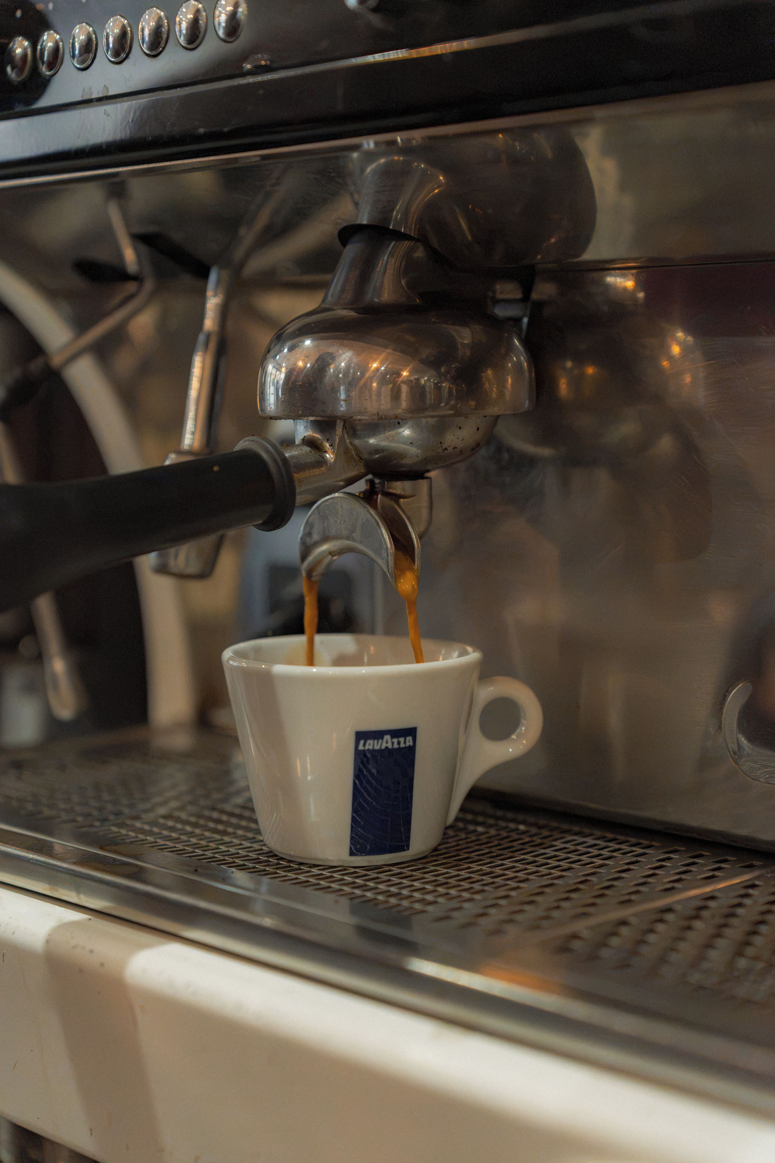 Una cafetera sirviendo espresso en una taza.