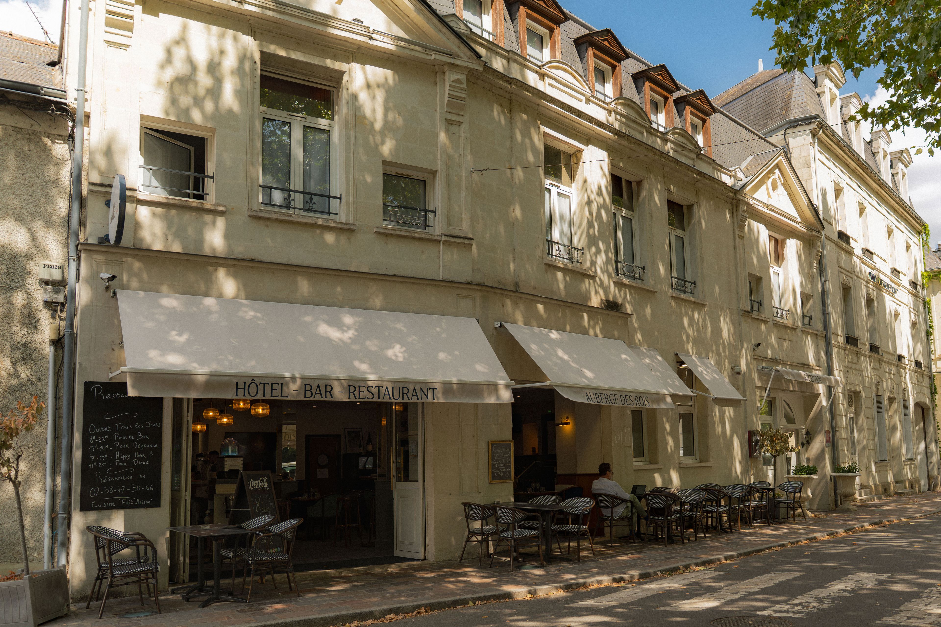 Un hôtel doté d’une terrasse et d’un panneau indiquant qu’il propose le petit-déjeuner.