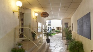A reception desk with a sign indicating the direction to the desk, a staircase with a handrail, and potted plants along the walkway. - Brit Hotel Chinon le Lion d'Or  (Chinon)