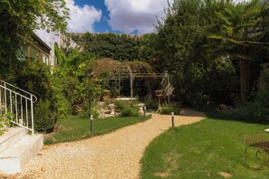 A garden pathway leading to a building with a white facade, surrounded by lush greenery and a clear sky. - Auberge des Rois - Chinon (Chinon)