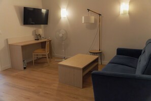 A living room with a TV, a desk, a chair, a fan, a lamp, and a sofa. - Auberge des Rois - Chinon (Chinon)