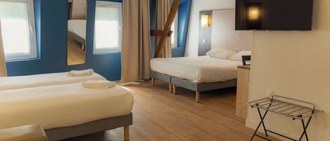 Habitación de hotel con dos camas, televisión, espejo y ventana.